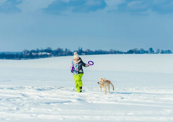 在雪地里带着狗跑的女孩 — 图库照片