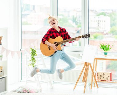 Mutlu genç kız gitarla zıplıyor