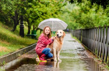 Küçük kız şemsiyesini köpekle paylaşıyor