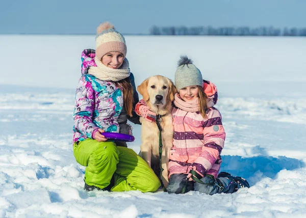 Schwestern umarmen Hund an einem Wintertag — Stockfoto