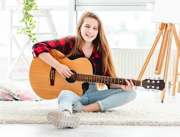 Söt flicka spelar gitarr sitter på golvet — Stockfoto