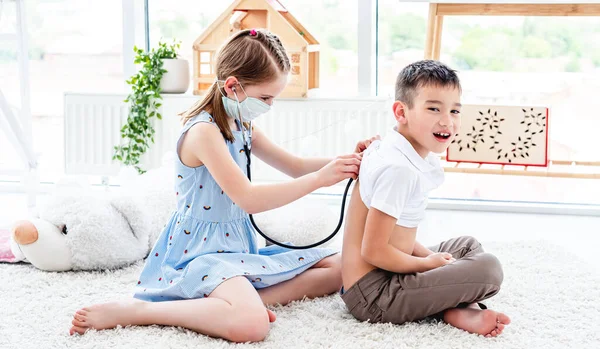 Menina com fonendoscópio menino escuta — Fotografia de Stock