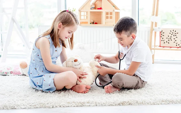 Діти грають лікаря з плюшевим ведмедем — стокове фото