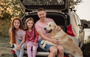Köpekli aile açık arabanın yanında.
