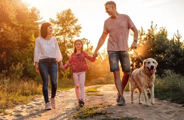 Familj med hund som går utomhus vid solnedgången — Stockfoto