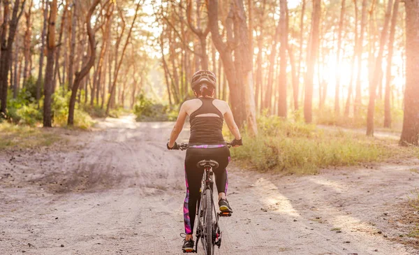 Girl riding bicycle along forest road — Stock Photo, Image