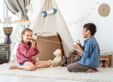 Çocuklar kendi yaptıkları telefonlarla oynuyorlar.