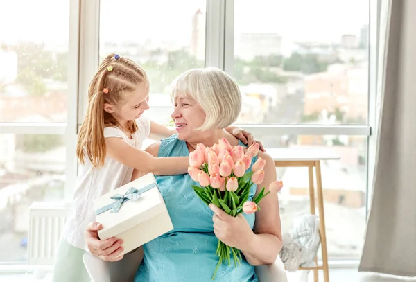 Lächelnde Oma mit Geschenken von Enkelin — Stockfoto