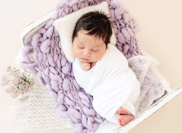 Divertido recién nacido descansando en una cama pequeña — Foto de Stock