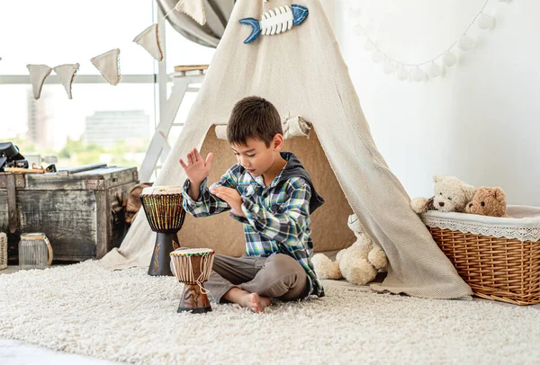 Маленький хлопчик грає джембе барабани в приміщенні — стокове фото