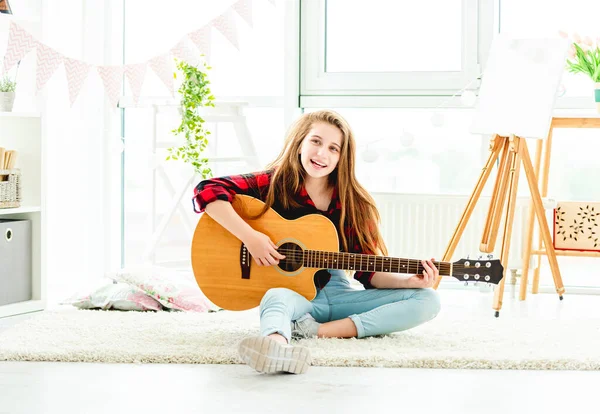 Hezká dívka hraje na kytaru sedí na podlaze — Stock fotografie