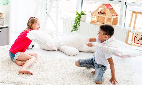 Little boy ang girl fighting pillows — Stock Photo, Image