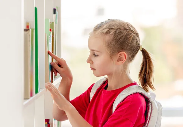 Studentessa cerca libro sullo scaffale della biblioteca — Foto Stock