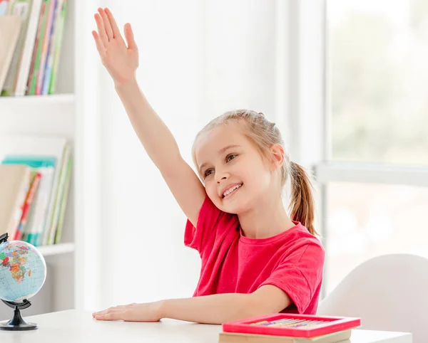 Smiling schoolgirl raising hand during lesson — Stock Photo, Image