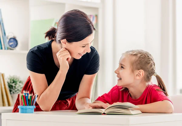 Lehrerin hilft Schülerin beim Lesen von Buch — Stockfoto