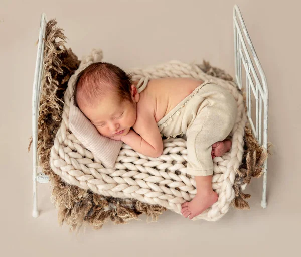 Divertido recién nacido durmiendo en una cama pequeña — Foto de Stock