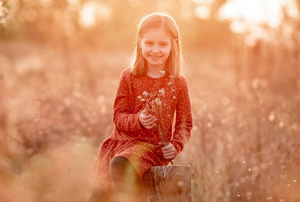 Klein meisje met herfstbloemen buiten — Stockfoto