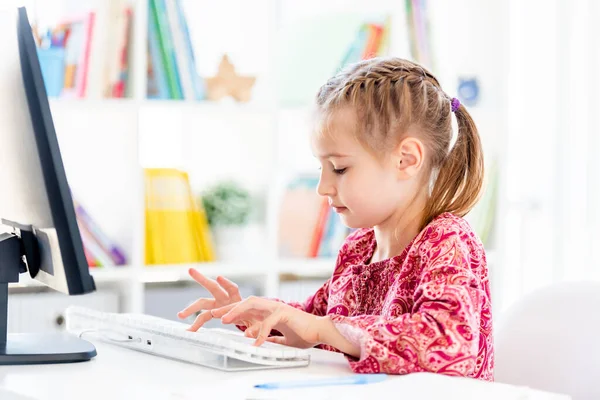 Klein meisje typen op computer toetsenbord — Stockfoto