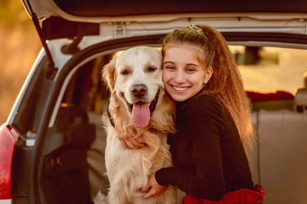 Genç kız arabanın bagajında köpeğe sarılıyor. — Stok fotoğraf