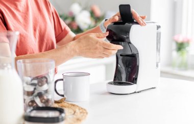 Evdeki kahve makinesinde kahve yapan bir kadının yakın çekimi.