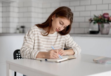 Mutlu kız evde, masada ödevini yapıyor.