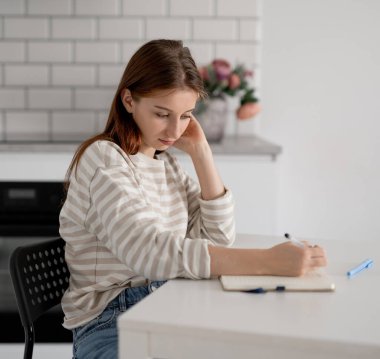 Mutlu kız evde, masada ödevini yapıyor.