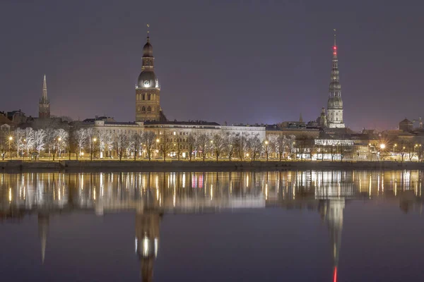 Vista noturna sobre o aterro do rio Daugava e as torres de igrejas em Riga — Fotografia de Stock