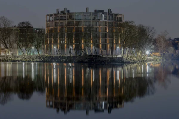 Riga (Lettonie), le 27 avril 2018. Immeuble de bureaux moderne avec ilumination nocturne, près de la rivière . — Photo