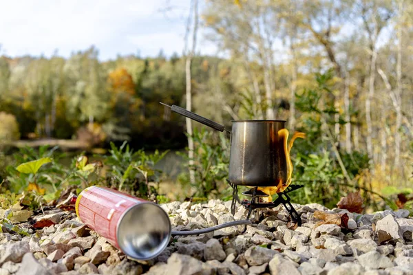 Portable tourist gas stove with a gray kettle on a background of nature in the mountains. Camping kitchen and tea. Unsafe gas stpve.