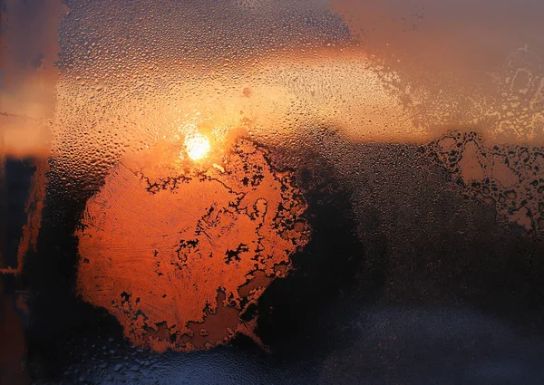 Padrões de gelo, gotas de água e luz solar em vidros de janela de inverno — Fotografia de Stock