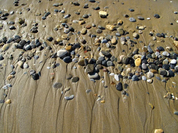 Влажные морские гальки на песке — стоковое фото