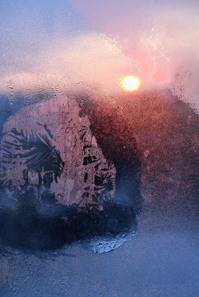 Ijspatronen, waterdruppels en zonlicht op een winter venster glasss — Stockfoto
