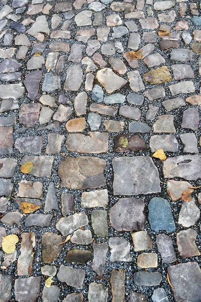 Vecchia pavimentazione di pietre di diversi colori e dimensioni — Foto Stock