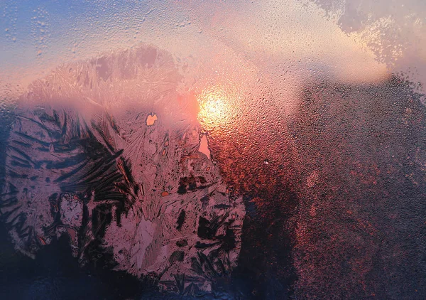 Ice patterns, water drops and sunlight on a window glass — ストック写真