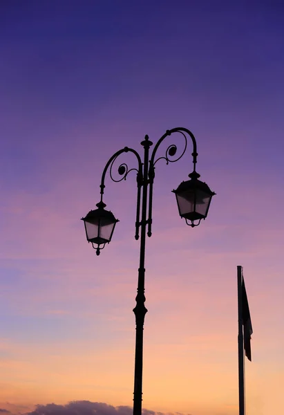Lâmpada de rua vintage bonita contra um céu brilhante do nascer do sol — Fotografia de Stock