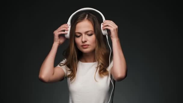 Hermosa mujer caucásica poniendo sus auriculares y sonriendo a la cámara . — Vídeo de stock