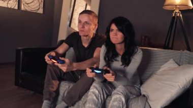 Konsolda video oyunu oynarken bir çift. Evde koltukta oturuyor. Kız WINS.