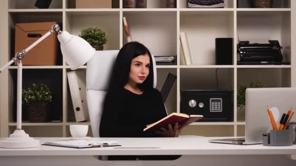 Woman at office. Visualizing something with her notebook. Then looking at camera — Stock Video
