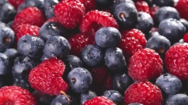 Taze yaban mersini ve plaka üzerinde dönen ahududu yığını. Closeup makro vurdu. Taze berry serisi. 4k.