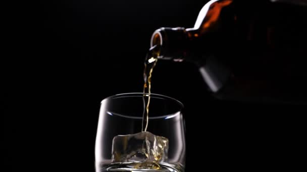 Виски наливается в стакан из бутылки. С кубиками льда . — стоковое видео