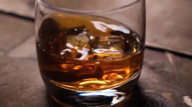 Dönen bardakta viski. Buz küpleri ile.