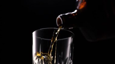 Whiskey pouring in the glass from the bottle. Without ice cubes.