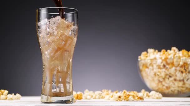 Zachte drank gieten in glas in de buurt van popcorn — Stockvideo