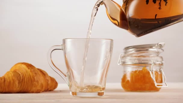 Persona anónima sirviendo té cerca de croissant y mermelada — Vídeos de Stock