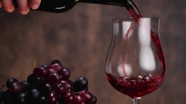 Bir avuç üzümün yanına şarap döken bir mahsul.
