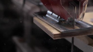 Tanınmayan marangoz elektrikli testereyle tahtayı kesiyor.