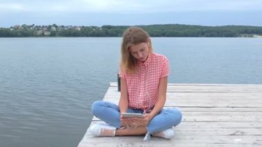 Tablet pc yakın göl ağır çekimde otururken izlemek güzel genç beyaz kadın