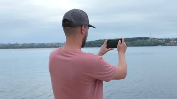 Young Bearded Caucasian Man Taking Photos While Standing Wide Lake — Stock Video