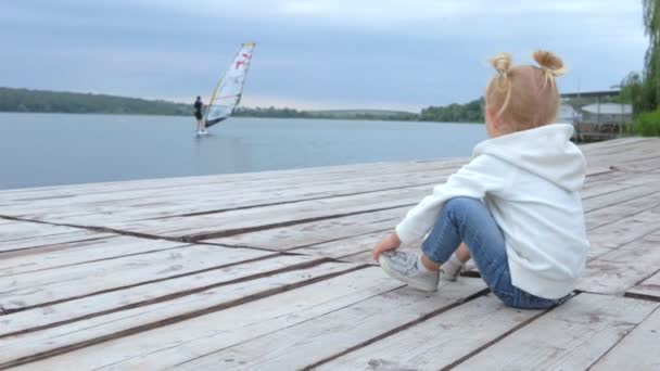 Menina Assistindo Windsurfista Girando Enquanto Sentado Perto Lago Câmera Lenta — Vídeo de Stock
