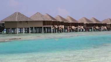 Su Villaları (Bungalovlar) ve yaz günü Maldivler 'deki tropik sahildeki ahşap köprü 